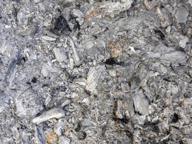 Üzerinde siyah ve siyah parçalar olan gri ve siyah taşlar yığını. Kayalar dağılmış ve yığın tek parça değil.