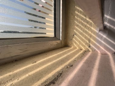 Duvarında gölge olan bir pencere pervazı. Gölge uzun ve ince, ve duvarda dökülüyor.