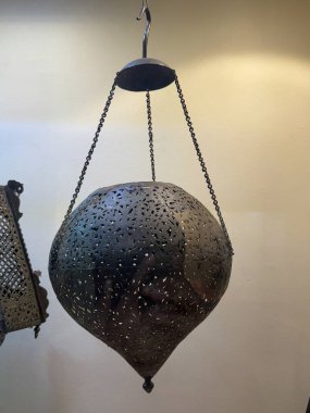 Üzerinde zincir sallanan bir fener. Fener metalden yapılmıştır ve eşsiz bir tasarımı vardır.