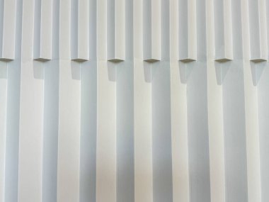 Beyaz çizgileri olan beyaz bir duvar. Çizgiler bir hareket ve yön duygusu yaratacak şekilde düzenlenmiş. Sahne sakin ve durgun, beyaz renk paletiyle