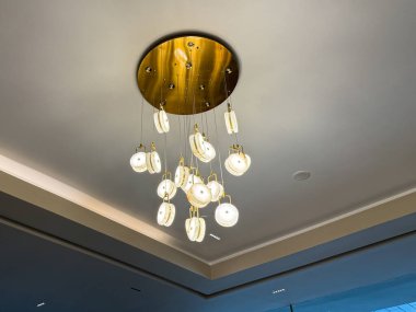 Tavanda altın ve beyaz bir avize asılı. Avize birçok küçük ışıktan oluşur ve tavandan sarkmaktadır.