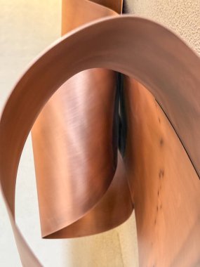 Duvarda asılı üç metal sanat eseri var. Sanat bakırdan yapılmıştır ve eşsiz, soyut bir tasarıma sahiptir. Parçalar bir hareket ve akış hissi yaratacak şekilde düzenlenmiş.