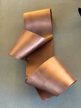 Duvarda asılı üç metal sanat eseri var. Sanat bakırdan yapılmıştır ve eşsiz, soyut bir tasarıma sahiptir. Parçalar bir hareket ve akış hissi yaratacak şekilde düzenlenmiş.