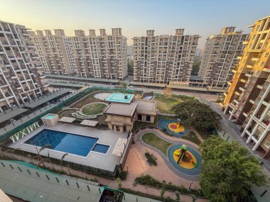 Havuzu ve oyun alanı olan bir yerleşim yeri manzarası. Havuz bir çitle çevrilidir ve oyun alanı bölgenin ortasındadır.