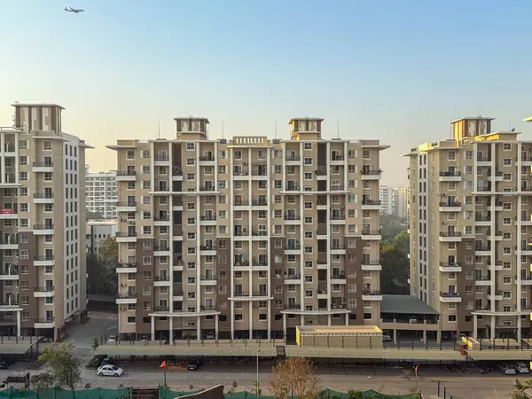 Beyaz çatılı büyük kahverengi ve bronz bir apartman dairesi. Bina bir otoparkla çevrili.