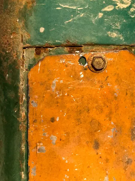 Yeşil çerçeveli paslı metal bir kapı. Kapı paslanmış ve ortasında bir delik var.