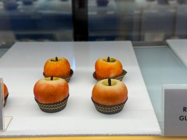 Dört küçük elma şekilli hamur işi. Pastalar turuncu ve yeşildir ve beyaz bir tabakta otururlar.