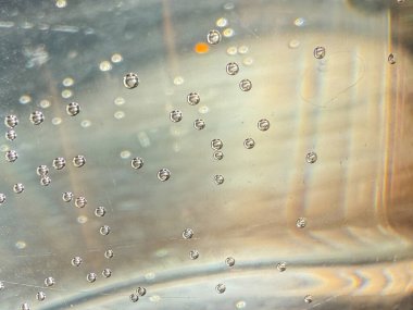 İçinde bir sürü köpük olan bir bardak su. Kabarcıklar camın her tarafına saçılmış. Kabarcıklar küçük ve yuvarlak