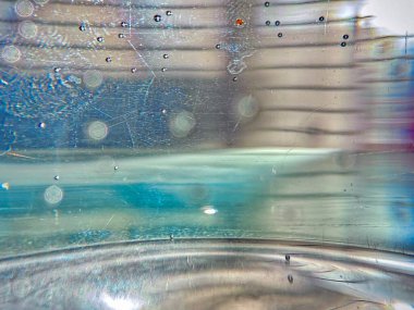 İçinde mavi bir sıvı olan bulanık bir cam görüntüsü. Sıvı fokurduyor gibi görünüyor ve bulanık bir görüntüsü var. Bu görüntünün hayali, ruhani bir kalitesi var.