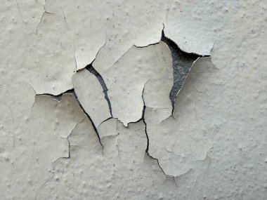 İçinde büyük bir çatlak olan bir duvar. Çatlaklar çok geniş ve derin. Duvar beyaz ve yarık ortasından görülüyor.