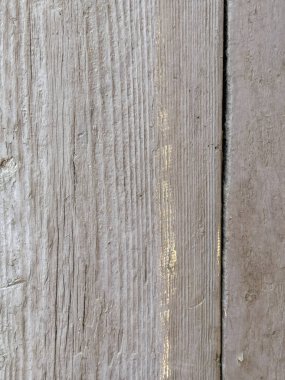 Tahta bir yüzey ve kumlu bir doku. Ahşap eski ve yıpranmış görünüyor. Bazı bölgelerde aşınma ve yırtık izleri var. Manzara kasvetli ve nostaljik.