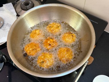 Fırında bir tencere kızarmış yemek pişiriliyor. Yemek kızarma aşamasında ve etrafı baloncuklarla çevrili.