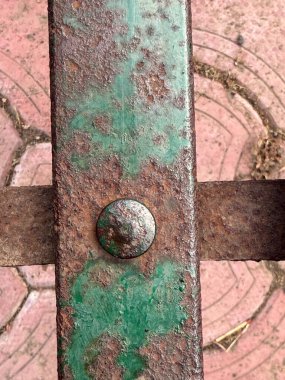 Üzerinde yeşil nokta olan paslı metal bir nesne. Yeşil nokta muhtemelen pas. Nem ve oksijene maruz kaldığı için metalin üzerinde oluşmuş.