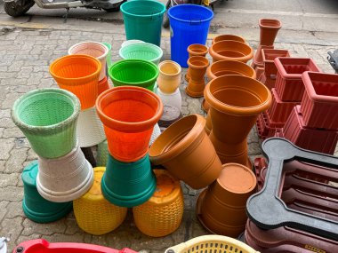 Farklı boylarda ve renklerde saksı ve saksı yığını. Tencereler öyle bir düzenlenmiş ki, düşecekmiş gibi görünüyorlar.