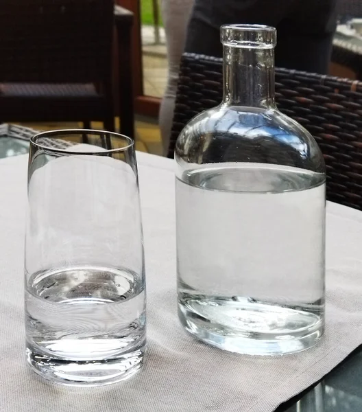 Clear glass bottles with drinking still water. Transparent set of bottle with glass on the table. Background.