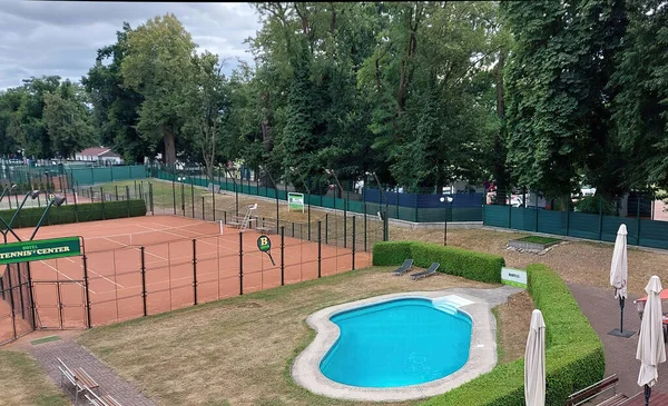 End of summer season. Empty sports complex. Tennis court with swimming pool absent at the end of summer, relaxation area in nature, in Europe.