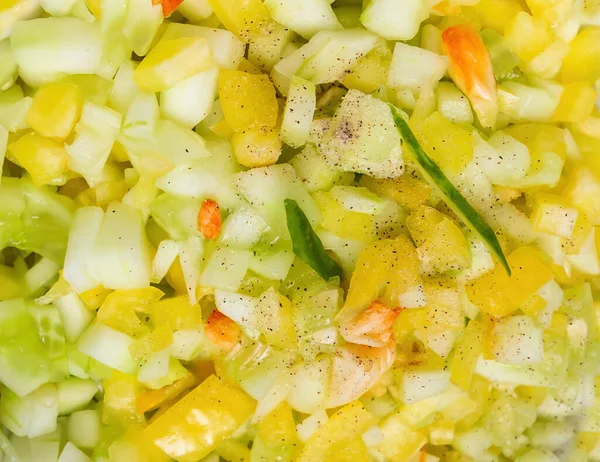 Chopped fresh vegetables on the background. Diet healthy vegetable salad with fresh colored peppers, cucumbers, onions and dressing.