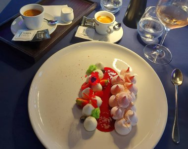 Bir fincan kahveyle dolu bir tabağın yakın çekimi ve zarif bir tatlıyla beyaz bir tabakta bir kaşık.