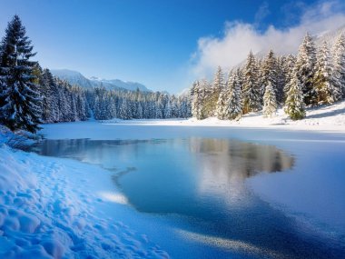 Dağlardaki karlı bir arazide güzel bir göl manzarası. Eriyen göl, güneşli hava, gökyüzündeki dağ sırtlarında sis. Duvar kağıdı, arkaplan.