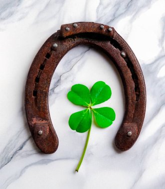 İyi şans için dört yapraklı yoncalı at nalı. Hasarlı bir at nalı fotoğrafı, iyi şans için batıl inanç. Hasarlı bir at nalı fotoğrafı, iyi şans için batıl inanç. Mermer arkaplan resimli, kolaj.