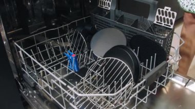 Bulaşık makinesine bulaşıkları yükleyen bir kız bulaşık makinesi, bulaşık makinesi, bulaşık makinesi, bulaşık makinesine yakın çekim, bulaşık makinesini dolduran ve kapayan bir kadın.