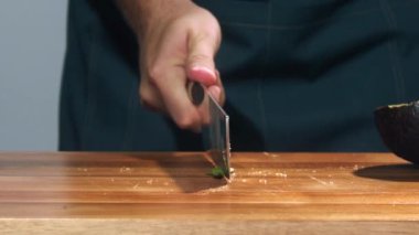 Şef avokadoyu yavaş çekimde kesiyor, avokadoyu yakın çekimde dilimliyor, avokado yavaş çekimde düşüyor, avokadoyu yakın çekimde düşürüyor.