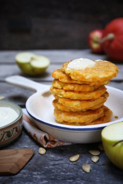 Stack of apple pumpkin pancakes with sour cream on wooden background