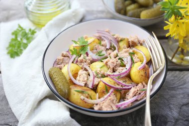 Ton balıklı patates salatası ve kırmızı soğan, zeytinyağı ve ahşap arka planda maydanoz sosu.