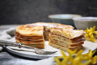 Fransız mutfağı. Matefaim. Elmalı Krepler yığını, bir fincan çay ve ahşap arka planda altın çanak.