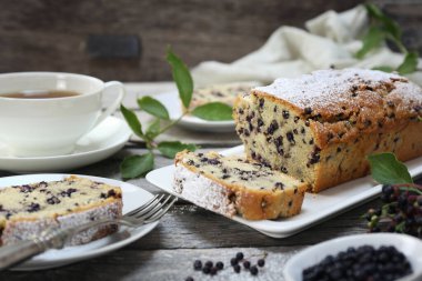 Yaz pastası. Gri ahşap arka planda çay partisi için siyah mürver pastası ve bir fincan çay. 