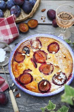 Damson mavisi erik pudingi (turta) ve bir bardak gül şarabı, krema şekeri ve badem sosu, ahşap zemin üzerinde Fransız mutfağı. Kırsal biçim, üst görünüm