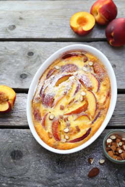 Bademli nektarin clafoutis (turta), krema sosu, ahşap arka planda Fransız mutfağı. en üstteki görünüm