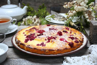 İtalyan tatlısı. Ahududu ekşi kremalı pasta, bir fincan çay ve çiçek açan beyaz akasya.