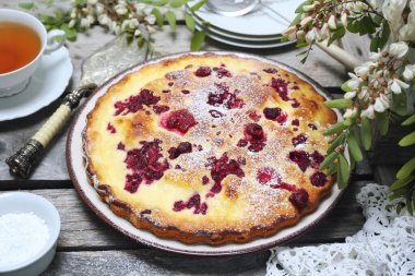 İtalyan tatlısı. Ahududu ekşi kremalı pasta, bir fincan çay ve çiçek açan beyaz akasya.