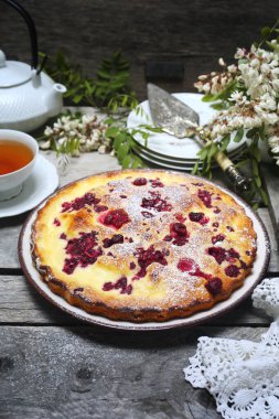 İtalyan tatlısı. Ahududu ekşi kremalı pasta, bir fincan çay ve çiçek açan beyaz akasya.