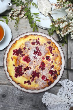 İtalyan tatlısı. Ahududu ekşi kremalı pasta, bir fincan çay ve çiçek açan beyaz akasya. Üst görünüm