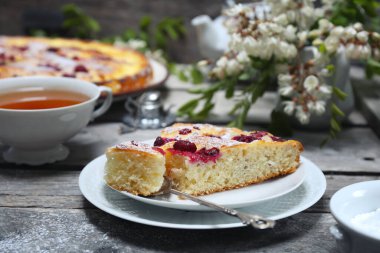 İtalyan tatlısı. Ahududu ekşi kremalı pasta, bir fincan çay ve çiçek açan beyaz akasya.