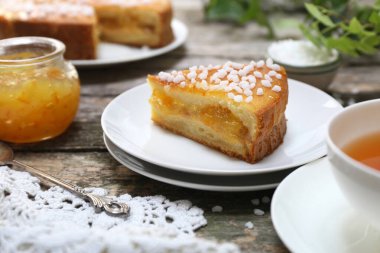 Portakal reçelli tatlı turta ve bir fincan çay, ahşap sırtta, seçici odaklı.