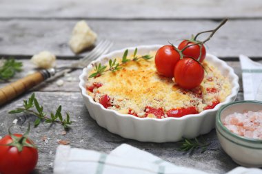 Aromatik bitkilerle domates ezmesi ve gri ahşap arka planda rendelenmiş parmesan peyniri.