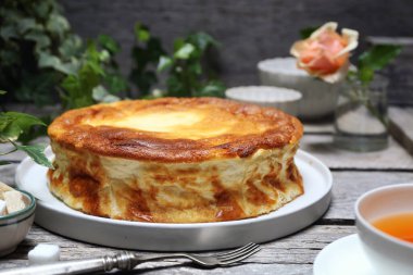 Unsuz Yunan yoğurtlu keki (bedava un, tereyağı, yağ). Gri ahşap arka planda üç tane turtalı sufle ve bir fincan çay.