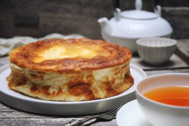 Unsuz Yunan yoğurtlu keki (bedava un, tereyağı, yağ). Gri ahşap arka planda üç sufle turtası ve bir fincan çay. Seçici odaklan