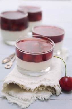 Işık yüzeyinde dört bardak kirazlı panna cotta. Seçici odaklan