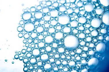 Mavi su kabarcıklarının makro çekimi arka planda hafif dalgalanmalar ve ışık yansımaları ile yüzeyde yoğun küme oluşturur