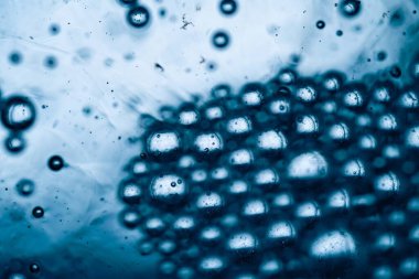 Mavi su kabarcıklarının makro çekimi arka planda hafif dalgalanmalar ve ışık yansımaları ile yüzeyde yoğun küme oluşturur