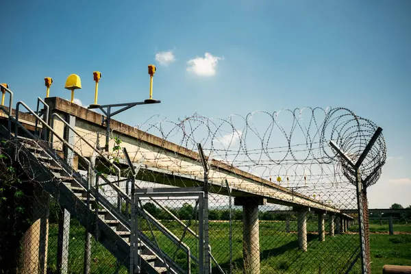 Havalimanı aydınlatma yapısı dikenli teller ve temiz mavi gökyüzünün altındaki merdivenlere erişim, çevre güvenlik kurulumu.