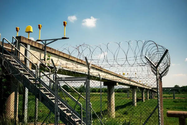 Havalimanı aydınlatma yapısı dikenli teller ve temiz mavi gökyüzünün altındaki merdivenlere erişim, çevre güvenlik kurulumu.