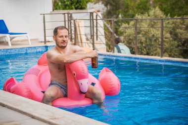 Flamingodaki neşeli adam havuzda eğleniyor. Havuz flamingosunda rahatlayan mutlu bir adam. Seyahat yaz tatili kavramı.