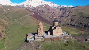 Gergeti Trinity Kilisesi 'nin, dağın üzerinden ağır sis bulutları akan hava aracı görüntüsü. Stepantsminda, Georgia yakınlarındaki karlı zirvelerin güzel dağ manzarası..