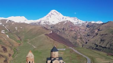 Gergeti Trinity Kilisesi 'nin, dağın üzerinden ağır sis bulutları akan hava aracı görüntüsü. Stepantsminda, Georgia yakınlarındaki karlı zirvelerin güzel dağ manzarası..