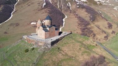 Gergeti Trinity Kilisesi 'nin, dağın üzerinden ağır sis bulutları akan hava aracı görüntüsü. Stepantsminda, Georgia yakınlarındaki karlı zirvelerin güzel dağ manzarası..
